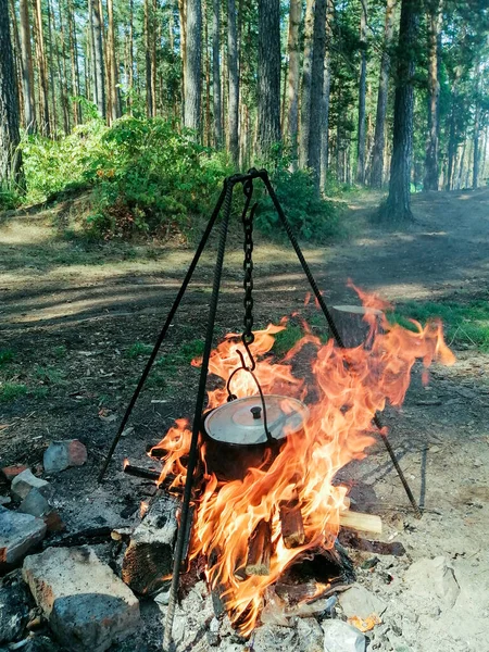 cooking food on a fire in a pot during a hike in the early morning