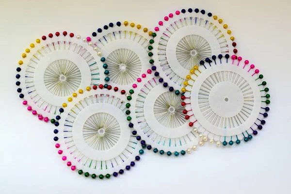 beyaz arka plan yakın plan üzerinde yuvarlak bir paket içinde farklı renkte yuvarlak bir başlık ile kırtasiye iğneleri