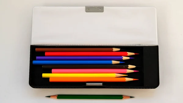 school pencil case with colored pencils on a white background
