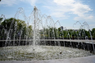 fountain in the city park against the background of the sky with clouds