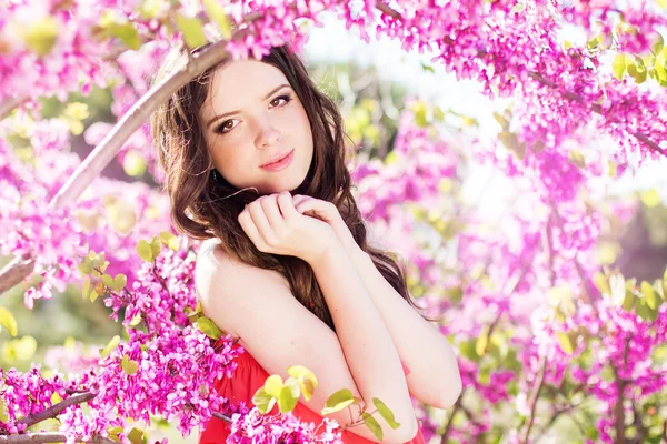 Pretty girl in spring park with pink flowers — Stock Photo, Image