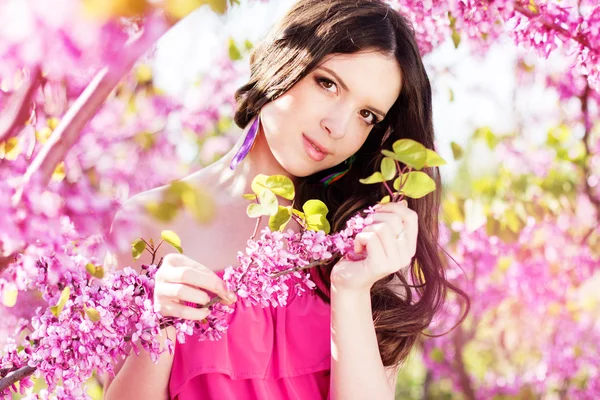 Mooi meisje in voorjaar park met roze bloemen — Stockfoto