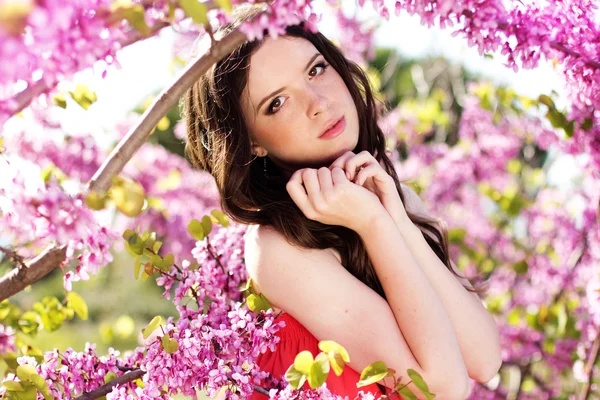 Jolie fille dans le parc de printemps avec des fleurs roses — Photo