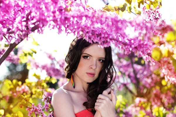 Jolie fille dans le parc de printemps avec des fleurs roses — Photo