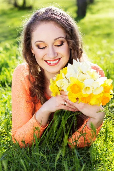 Menina sorridente feliz com flores amarelas narcisos — Fotografia de Stock