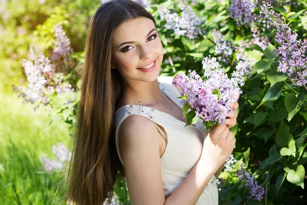 Schöne Mädchen mit einem Flieder Blumen — Stockfoto