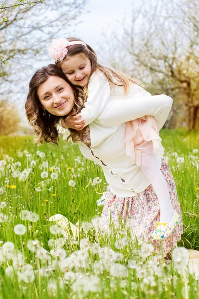 Moeder en dochter in veld met paardebloemen — Stockfoto