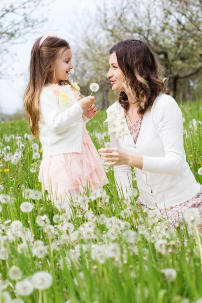 Moeder en dochter in veld met paardebloemen — Stockfoto