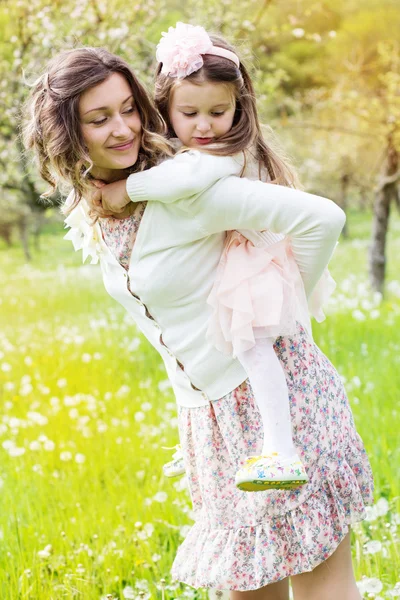 Mother and daughter in field with dandelions — Stock Photo, Image