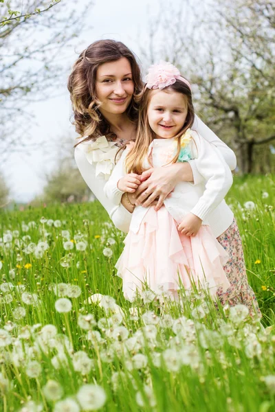 Moeder en dochter in veld met paardebloemen — Stockfoto