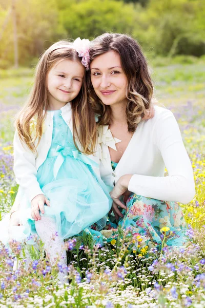 Mother and daughter in field with colorful flowers — Stock Photo, Image