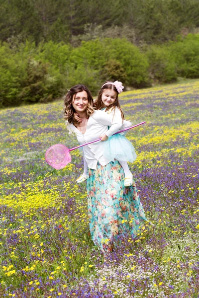 Mãe e filha no campo com flores coloridas — Fotografia de Stock
