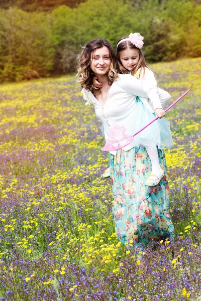 Mãe e filha no campo com flores coloridas — Fotografia de Stock