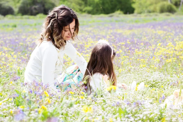 Mother and daughter in field with colorful flowers — Stock Photo, Image