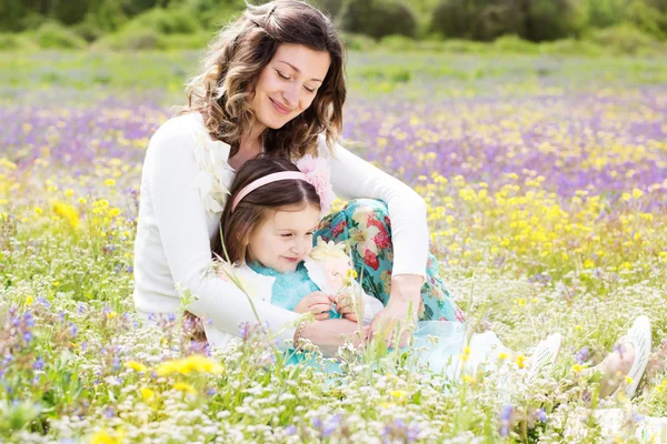 Mor och dotter i fält med färgglada blommor — Stockfoto