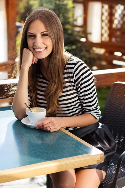 Jonge vrouw drinken koffie in een café in de buitenlucht — Stockfoto