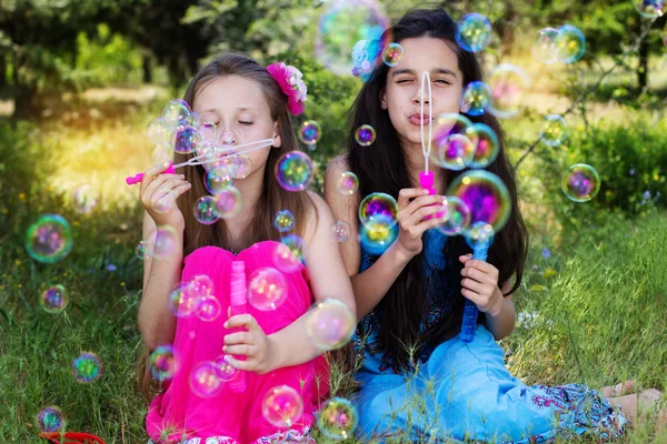 Retrato de duas meninas brincando com o ventilador de bolhas — Fotografia de Stock