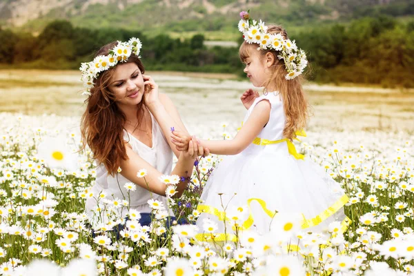 Mother with her child playing in camomile field — Stock Photo, Image