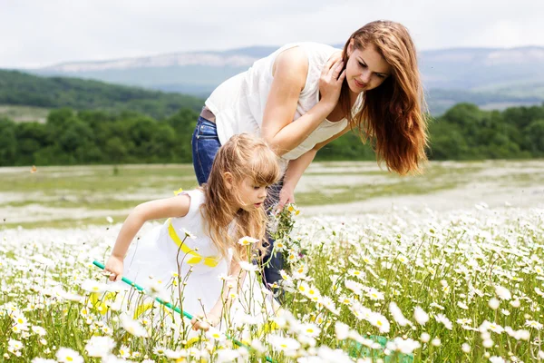 Mother with her child playing in camomile field — Stock Photo, Image