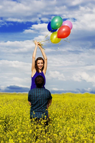 Pareja feliz con globos en el campo amarillo —  Fotos de Stock