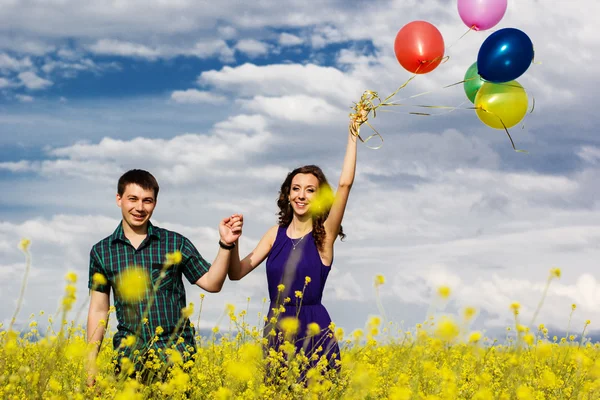 Joyeux couple avec des ballons sur le terrain jaune — Photo