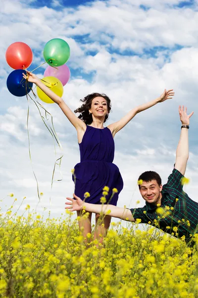 Happy couple with balloons on the yellow field — Stock Photo, Image