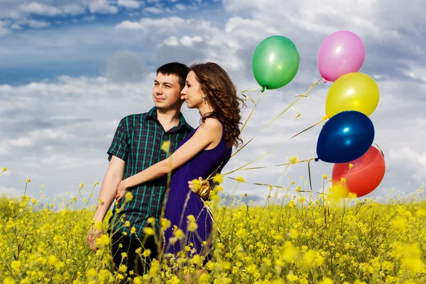 Casal feliz com balões no campo amarelo — Fotografia de Stock