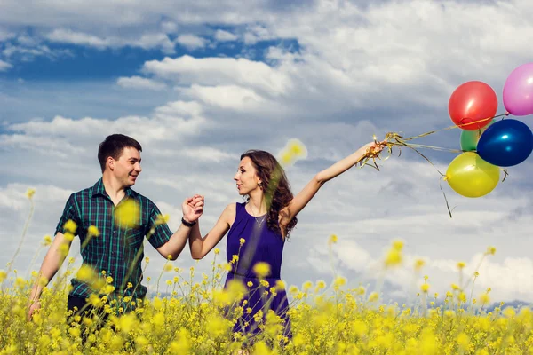 Coppia felice con palloncini sul campo giallo — Foto Stock