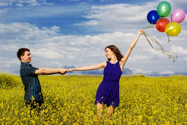 Glückliches Paar mit Luftballons auf dem gelben Feld — Stockfoto