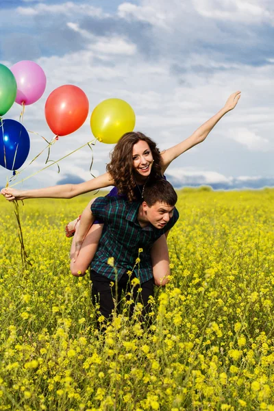Счастливая пара с воздушными шарами на желтом поле — стоковое фото