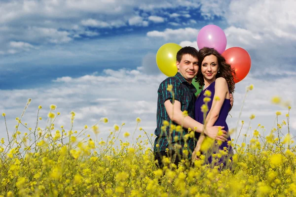 Happy couple with balloons on the yellow field — Stock Photo, Image