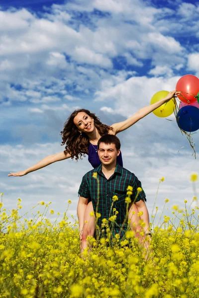 黄色のフィールドに風船で幸せなカップル — ストック写真