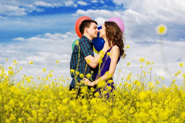 Casal feliz com balões no campo amarelo — Fotografia de Stock