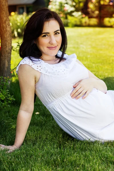 Pregnant woman resting in park with green grass — Stock Photo, Image