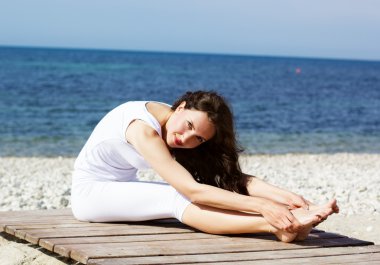 Deniz kıyısında yoga egzersizleri yapıyor kız