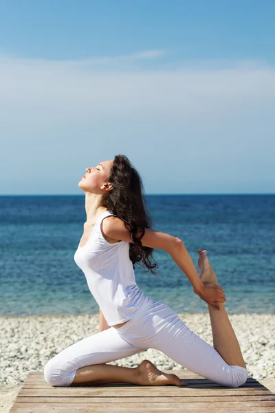 Meisje doen yoga oefeningen aan de kust van de zee — Stockfoto