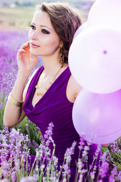 Entzückendes Mädchen mit lila Luftballons. — Stockfoto