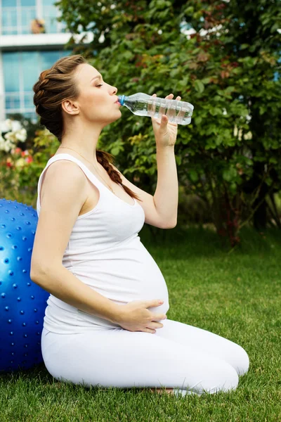 Mulher grávida bonita relaxante no parque — Fotografia de Stock