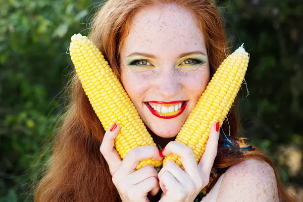 Smiling girl with freckles holding corn cob Royalty Free Stock Images