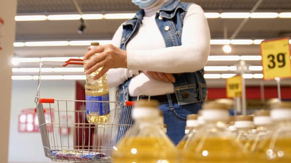 Buyer chooses vegetable oil in the supermarket. Shopping in the store.