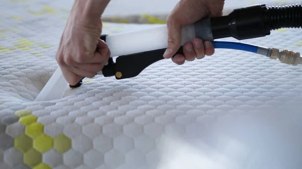 Male Worker Cleaning a mattress With Vacuum Cleaner.Professionally extraction method. Upholstered furniture. Mattress chemical cleaning.