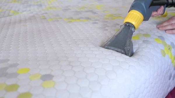 Male Worker Cleaning a mattress With Vacuum Cleaner.Professionally extraction method. Upholstered furniture. Mattress chemical cleaning.