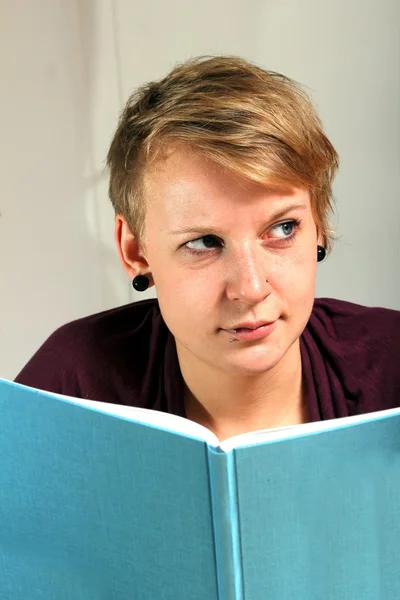 Critically looking girl is reading a book — Stock Photo, Image