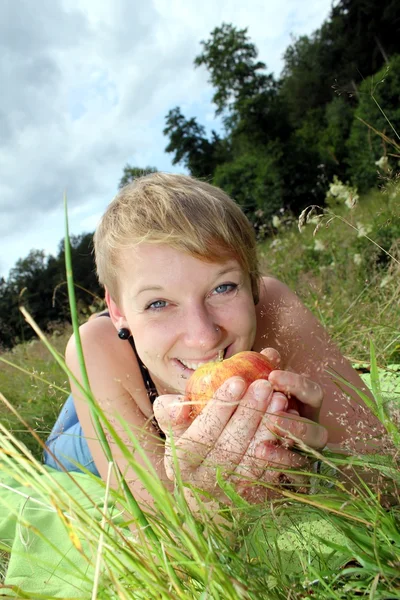 Girl with apple on summer meadow — Stock Photo, Image