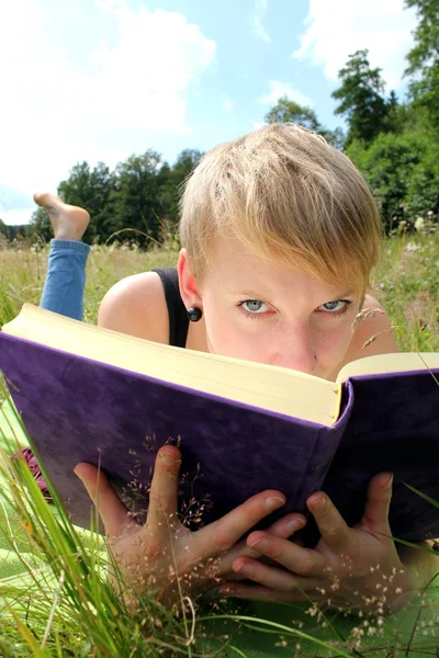 Girl is reading a book on a summer meadow — Stock Photo, Image