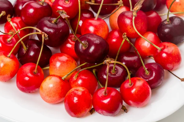 Reife Kirschen auf einem weißen Teller — Stockfoto