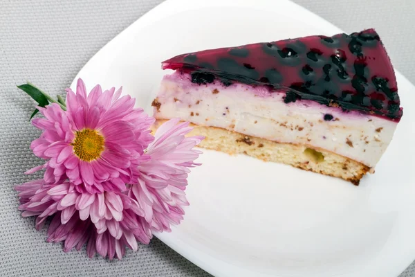 Piece of blueberry cake and asters — Stock Photo, Image