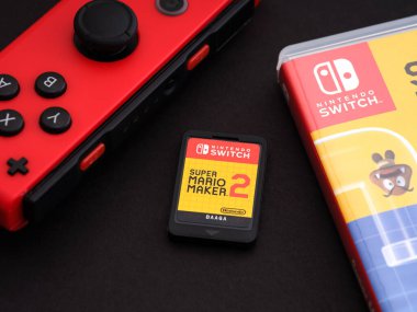 Tambov, Rusya Federasyonu - 28 Eylül 2021 Nintendo Switch Super Mario Maker 2 video oyunu kartuşu, oyun kutusu ve siyah arka planda kırmızı Joy-Con.