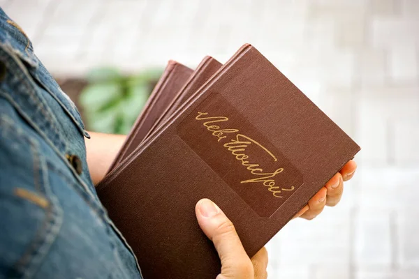 一个手里拿着列夫 托尔斯泰的书的女人利奥 托尔斯泰在书的精装本上以俄文手写签名 免版税图库图片