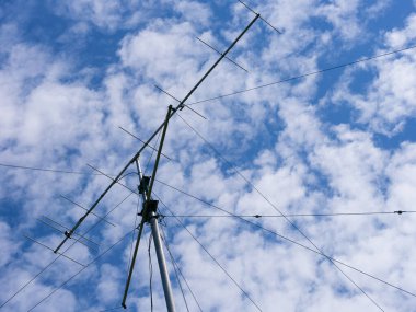 Bulutlu bir gökyüzüne karşı sabit ipli VHF radyo anteni
